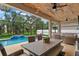 Covered outdoor patio with string lights, dining table, and a view of the screened-in pool at 7114 Mill Hopper Ct, Palmetto, FL 34221