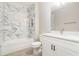 Bathroom with a large white marbled tiled wall over the tub and a white vanity with a large mirror at 14362 San Domingo Blvd, Port Charlotte, FL 33981