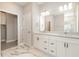 Bathroom with double sinks, marble countertops, and a tiled shower and decorative flooring at 14362 San Domingo Blvd, Port Charlotte, FL 33981