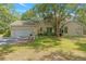 Well-maintained home featuring a two-car garage, a lush lawn and mature trees providing shade at 11933 Pasco Trails Blvd, Spring Hill, FL 34610
