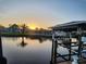 Waterfront sunset scene with a boat dock and palm trees reflecting on the water at 3510 Magnolia Way, Punta Gorda, FL 33950
