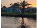 A waterfront view featuring a house and palm tree reflected in the water at sunset at 3510 Magnolia Way, Punta Gorda, FL 33950