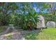 Wooden shed nestled amongst tropical plants and a greenhouse at 1026 Roosevelt Ave, Spring Hill, FL 34604