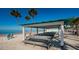 Beach pavilion with picnic tables offers a shady spot near the ocean, surrounded by palm trees at 4736 Jasper Dr # 207, New Port Richey, FL 34652