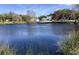 Scenic pond view with a dock offers a tranquil setting, enhanced by lush greenery and clear skies at 4736 Jasper Dr # 207, New Port Richey, FL 34652