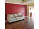 Open concept living room featuring wood floors, red accent wall and view to the kitchen at 1873 Mazo Mnr # T5, Lutz, FL 33558