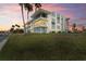 Modern, three-story condo building with vibrant blue accents and palm trees in the well-manicured lawn at 770 Island Way # N302, Clearwater, FL 33767