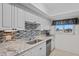Updated kitchen featuring granite countertops, mosaic backsplash, white cabinets and stainless steel appliances at 770 Island Way # N302, Clearwater, FL 33767