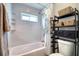 Bright bathroom with a tiled shower and tub combo, featuring a sleek storage rack and a window for natural light at 13753 Judy Ave, Hudson, FL 34667