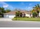 Charming single-story home featuring a well-manicured lawn, mature trees, and a three-car garage at 21312 Preservation Dr, Land O Lakes, FL 34638