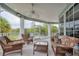 Relaxing screened porch with wicker furniture and ceiling fan, overlooking a tranquil view at 7352 Gulf Way, Hudson, FL 34667