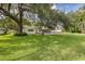 Large backyard with lush green grass, a pool, and a large shade tree at 12709 Clock Tower Pkwy, Hudson, FL 34667