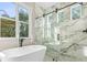Elegant bathroom featuring a soaking tub, glass-enclosed shower with marble tile, and a large window at 9229 Creston Ave, New Port Richey, FL 34654