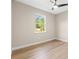 Spacious bedroom featuring modern ceiling fan, light beige walls, wood-look flooring and a bright window at 9229 Creston Ave, New Port Richey, FL 34654