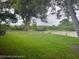 Spacious backyard featuring a pond, green grass and mature trees at 7278 Scotland Cir, Weeki Wachee, FL 34613