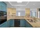 Modern kitchen with teal cabinets, granite countertops, and stainless steel appliances at 3849 Staysail Ln, Holiday, FL 34691