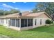 Back exterior showing a screened porch, tan colored building, and grassy yard at 3849 Staysail Ln, Holiday, FL 34691