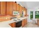 Kitchen with oak cabinets, tile backsplash, and view to backyard at 9108 Bassett Ln # B, New Port Richey, FL 34655