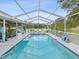 Inviting pool area with covered patio, lounge chairs, and lush landscaping at 1096 Florian Way, Spring Hill, FL 34609