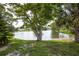 Picturesque backyard with a sandy beach area, mature trees, and a tranquil view of the beautiful lake at 12307 Fieldstone Ln, Hudson, FL 34667
