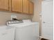 Bright laundry room with wood cabinets and full-size washer and dryer at 11724 Heritage Point Dr, Hudson, FL 34667