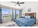 Main bedroom with large windows, blue bedding, and ceiling fan at 13521 Stacey Dr, Hudson, FL 34667