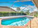 Beautiful swimming pool surrounded by a screen enclosure, brick patio, and greenery at 8726 Latham Drive, Hudson, FL 34667