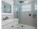 Modern bathroom with gray tile, frameless shower, and white vanity at 3448 Triggerfish Dr, Hernando Beach, FL 34607