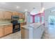 Modern kitchen with light wood cabinets, black appliances, and an island at 1183 Mystic Ct, Spring Hill, FL 34609