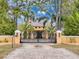 An elegant yellow home featuring a secured gated entrance and paved driveway framed by lush trees at 11430 Trotting Down Dr, Odessa, FL 33556