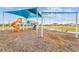 Community playground with a shade cover, swings, and a slide, offering a safe and fun outdoor space at 31941 Blue Passing Loop, Wesley Chapel, FL 33545