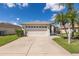 Tan house with a two car garage and landscaping at 1633 Arbor Knoll Loop, Trinity, FL 34655