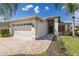 Single story home with tan exterior, light colored garage door and a paved walkway at 1633 Arbor Knoll Loop, Trinity, FL 34655