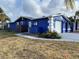 Side view of a blue home with attached garage, landscaping, and a walkway at 7446 Donegal St, New Port Richey, FL 34653