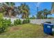 Fenced backyard featuring a lush lawn, manicured hedges, and tropical palm trees on a sunny day at 800 61St N St, St Petersburg, FL 33710