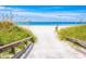 Scenic boardwalk leading to a pristine white sand beach with clear blue waters and lush green dunes at 800 61St N St, St Petersburg, FL 33710