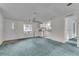 Spacious living room with teal carpet and view into kitchen at 9520 Merton St, New Port Richey, FL 34654