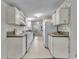 White kitchen cabinets, floral wallpaper, and appliances at 9520 Merton St, New Port Richey, FL 34654