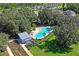Aerial view of a community pool surrounded by trees, lounge chairs, and cabana at 3893 Burdick Loop, Odessa, FL 33556
