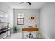 Bright home office features a wooden desk with gold accents, a modern clock, and neutral décor at 3893 Burdick Loop, Odessa, FL 33556