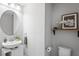 Well-lit powder room with a modern sink, round mirror, and decorative accents at 3893 Burdick Loop, Odessa, FL 33556