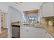 Bright kitchen featuring granite counters, stainless steel dishwasher, and white cabinetry, with views to the screened patio at 8210 Aquila St # 227, Port Richey, FL 34668