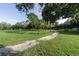 Scenic park view featuring a walking path through a grassy lawn, surrounded by mature trees under a bright blue sky at 6635 Stewart N Ave, St Petersburg, FL 33702