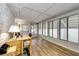 Bright sunroom featuring wood-look floors, large windows, and a dedicated desk space for a home office setup at 6635 Stewart N Ave, St Petersburg, FL 33702