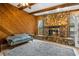 Cozy living room featuring a stone fireplace and wood-paneled walls at 7504 Cypress Knee Dr, Hudson, FL 34667