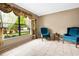Bright living room with two teal armchairs and view of the front yard at 7504 Cypress Knee Dr, Hudson, FL 34667