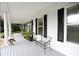 Front porch with white columns, black shutters and metal bench at 23337 Lake Lindsey Rd, Brooksville, FL 34601