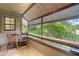 Screened porch with wooden chairs and tranquil wooded views at 303 Old Mill Pond Rd # 303, Palm Harbor, FL 34683
