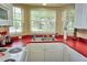 Bright kitchen featuring white cabinets, red countertops and stainless steel sink at 2077 Wetland Pt # 1103, Lutz, FL 33558