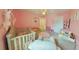 Adorable pink themed bedroom with a green crib, toys, and a white door at 5825 Grand Sonata Ave, Lutz, FL 33558